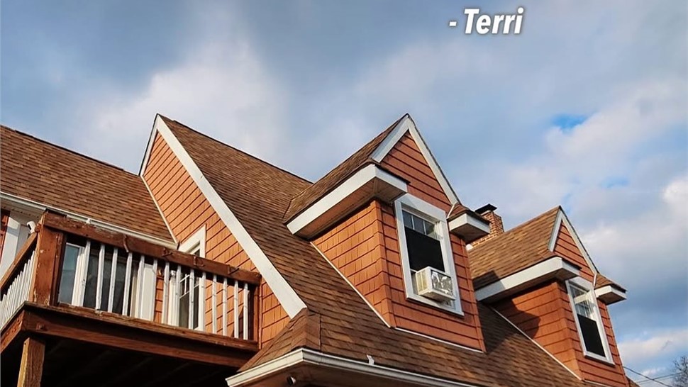 Close up of a home with cedar style siding and roofing featured in Warner Exteriors review graphic.