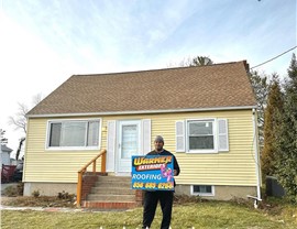 Homeowner holding Warner Exteriors roofing sign after roof replacement project.