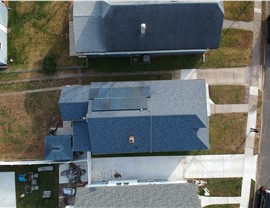 Compact solar panel installation on a blue shingle roof captured from an overhead drone perspective