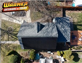 Black solar panel system installed vertically on the rear roof face of a New Jersey home