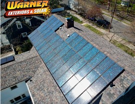 Solar panel array installed on a residential shingle roof in New Jersey shown from an elevated drone angle