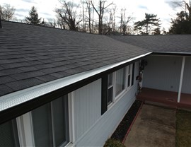 Gutter guards installed along roofline of white New Jersey home to prevent clogs and improve drainage