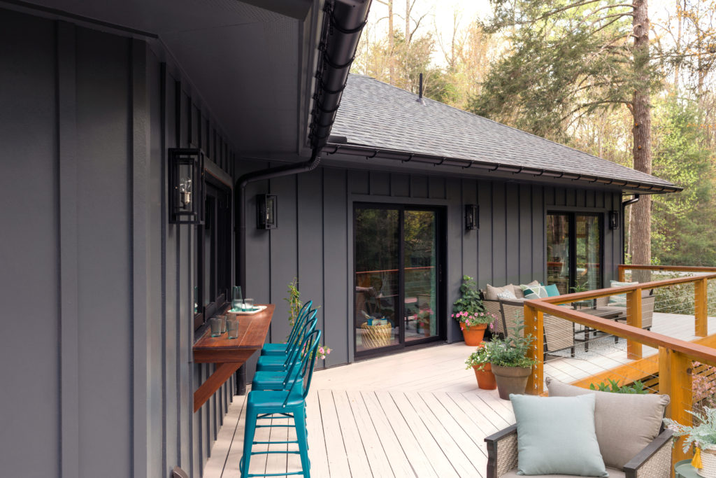 a black board and batten siding on a home in the woods fits the high contrast home style trends for 2022