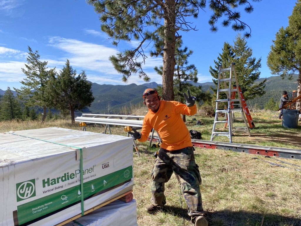 WestPro siding installer smiles and gives a thumbs up next to James Hardie siding at a Boulder County home