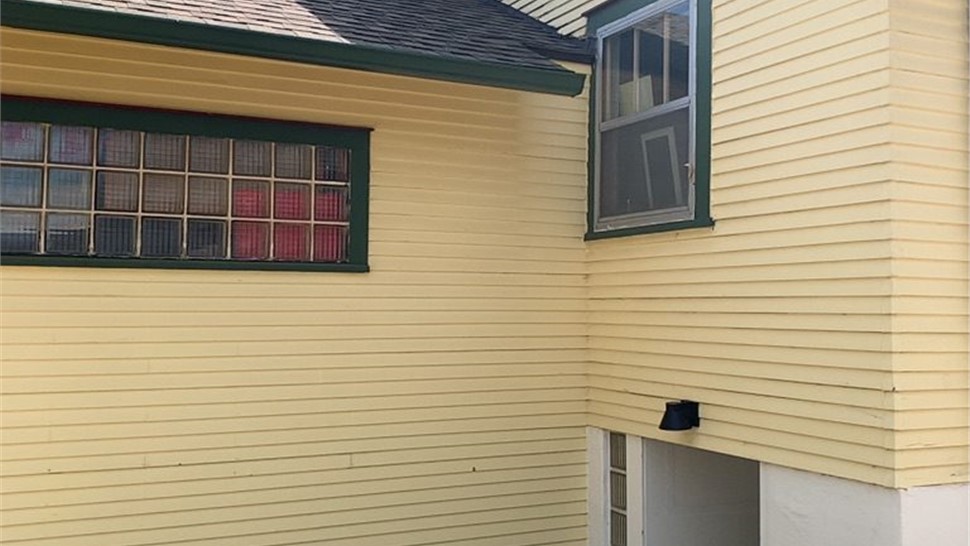 Side elevation of a Longmont home showing an original upper window and basement window before replacement
