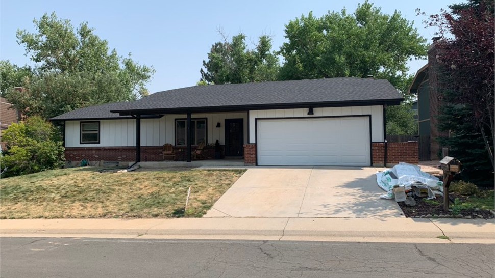 Completed roofing, siding, and window replacement using Arctic White Board and Batten, GAF Armorshield Shingles in Charcoal, and Alside Mezz Vinyl windows in White on home in Westminster Colorado