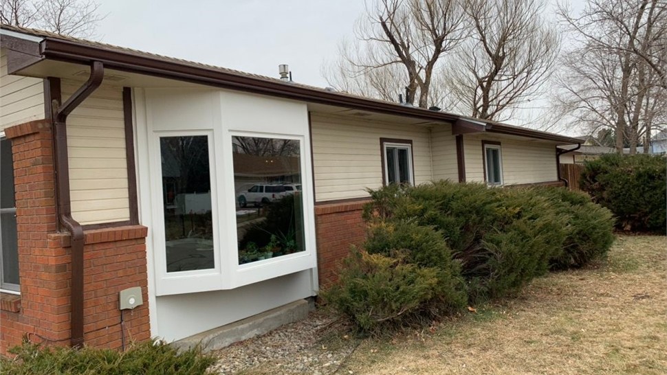 Tan composite lap siding around a front bay window before replacement, Longmont, CO