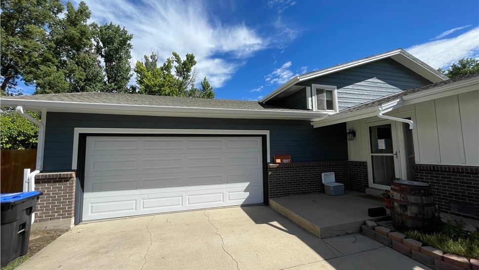 Completed James Hardie siding replacement with Eveni8ng Blue lap siding and Arctic White Board and Batten accents and new gutter system replacement on home in Arvada Colorado