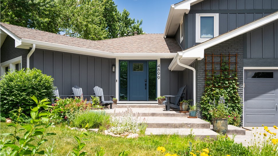 Boulder Home after full reside, window and entry door replacement with all new trim, soffit, fascia and gutters, in primed and painted James Hardie Board and Batten