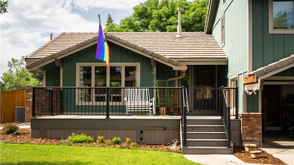 Teal vertical-groove wood siding and tan window trim at the front entry of a Longmont home
