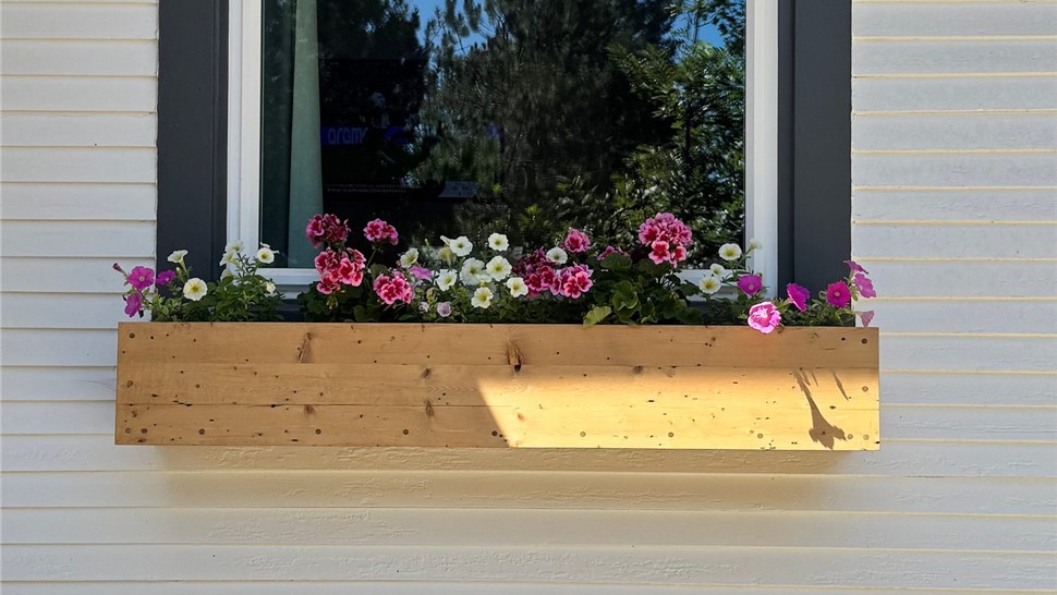 Close-up of a window and flower box on the home's white repainted siding