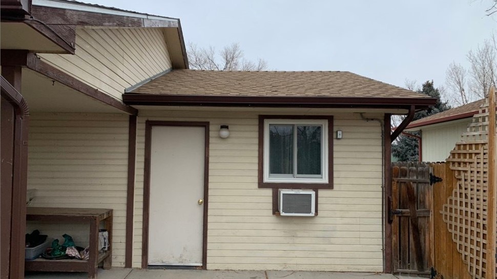 Tan composite siding on garage side wall before replacement, Longmont, CO