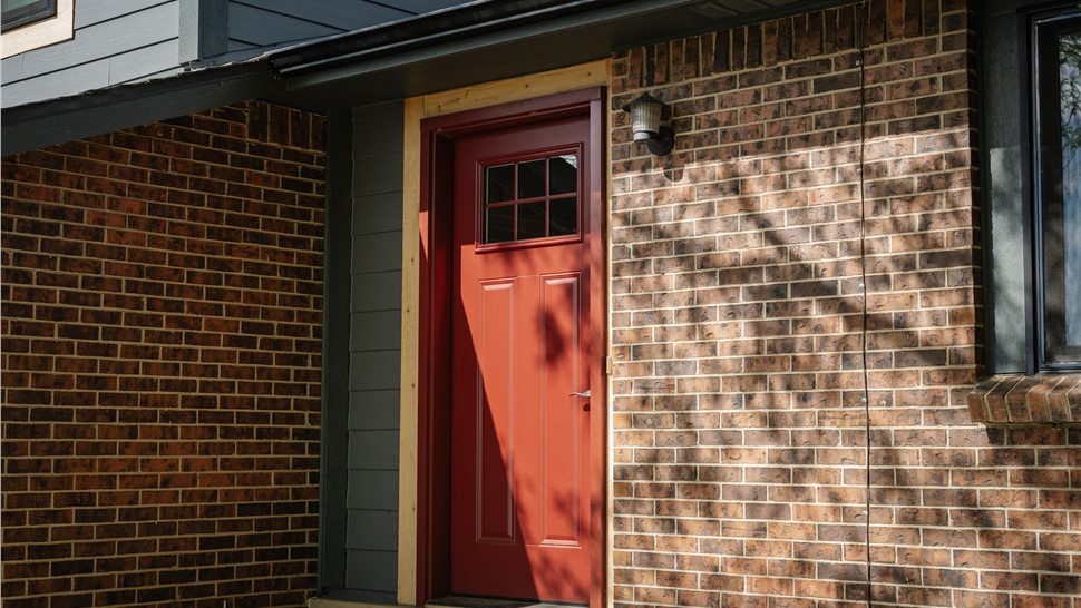 Red entry door and brick facade preserved on a Westminster, CO home
