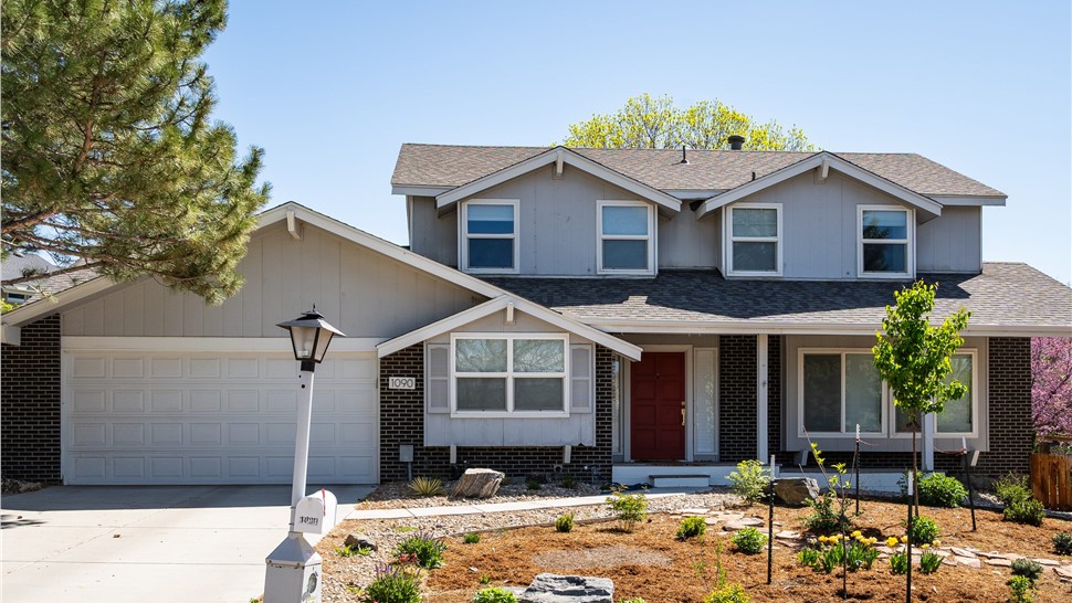 Two-story Longmont home with light gray Masonite siding above dark brick before James Hardie siding replacement