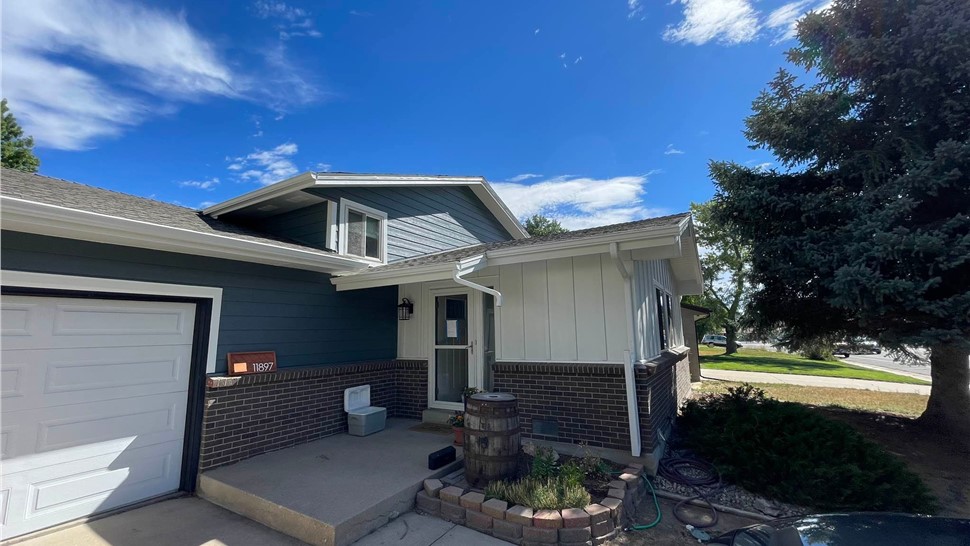 Completed James Hardie siding replacement with Eveni8ng Blue lap siding and Arctic White Board and Batten accents and new gutter system replacement on home in Arvada Colorado