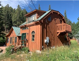 Aging wood board and batten siding and cedar shake dormer roof on a multi-story mountain home in Nederland, Colorado
