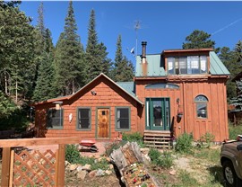 Full front exterior of a wood-sided mountain home in Nederland, Colorado, before siding replacement