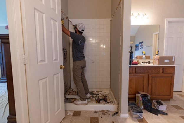 Photo of a ZINTEX contractor working on a walk in shower and demolishing the existing tile to replace with acrylic panels