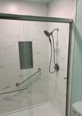 Photo of a walk-in shower with solid surface walls.