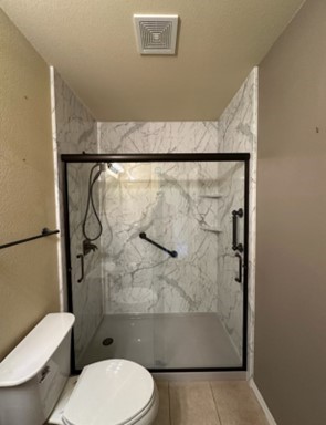 Photo of a walk in shower with acrylic walls and a glass door remodeled by ZINTEX